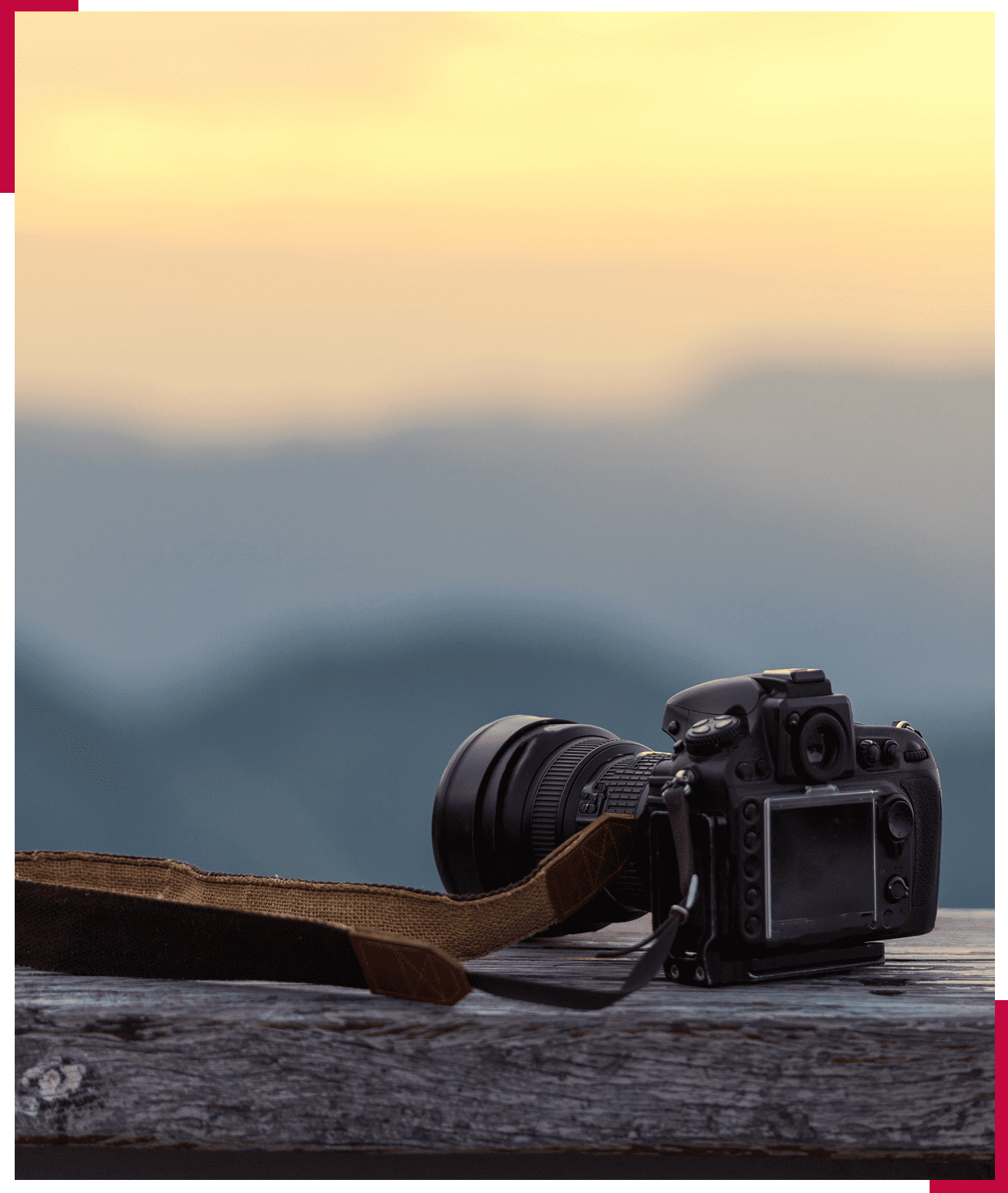 Camera resting on wooden surface, scenic background.